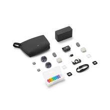 ಗ್ಯಾಲರಿ ವೀಕ್ಷಕಕ್ಕೆ ಚಿತ್ರವನ್ನು ಲೋಡ್ ಮಾಡಿ, DJI Mic Mini 2S kit contents laid out on a white background: charging case, black carry pouch, receiver, two transmitters, two fluffy windscreens, clips, magnetic covers in white and black, a box of eight colorful covers, a USB-C cable, an audio cable, and an adapter.

